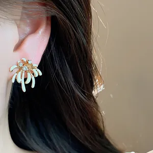 Close-up of elegant firework stud earrings with 18k gold plating and white enamel