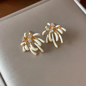 Detail view of gold-plated firework stud earrings with white enamel and sparkling zircons