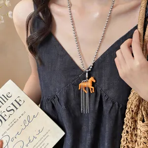 Detail view of a chic resin horse pendant necklace worn with a black summer dress