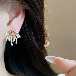 Close-up of 18k gold plated firework stud earring with white enamel and zircons