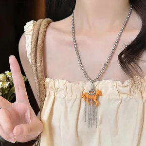 Detail view of a stylish playful brown resin horse pendant necklace worn by a fashion model