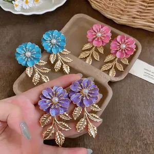 Makroansicht bunter Emaille-Blumenohrringe mit goldenen Blattquasten und Perlen