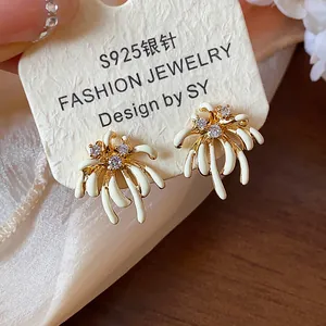 Detailed view of gold-plated firework earrings with white enamel and zircons