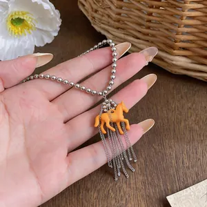 Close-up of a whimsical resin horse pendant necklace with silver chain tassels