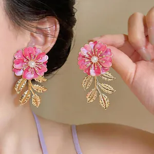 Detailansicht der rosa Emaille-Ohrringe mit Goldblatt und Perlenakzenten.