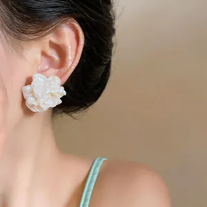 Dettaglio ravvicinato di un delicato orecchino a fiore in resina crema su una modella
