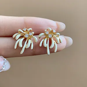 Detailed close-up of gold-plated fireworks stud earrings with white enamel and zircons