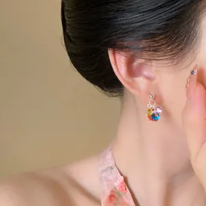 Primer plano de pendientes de borla con cuentas de colores estilo dopamina puestos en oreja