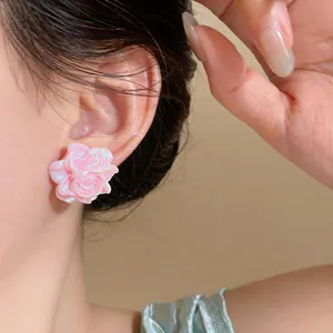 Primo piano di eleganti orecchini a lobo a rosa in resina rosa indossati per stile