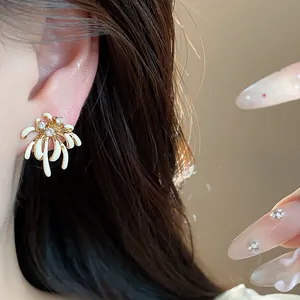 Close-up of elegant firework-shaped 18k gold plated stud earring with zircons and enamel.