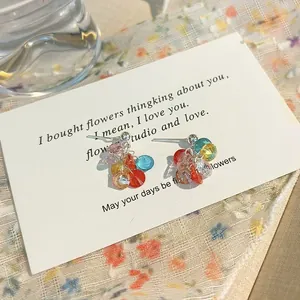 Pendientes de borla con cuentas de cristal multicolores en una tarjeta decorativa blanca