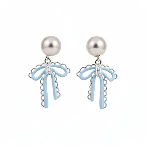 Elegant light blue bow earrings with white pearls and zircons on a clean background.