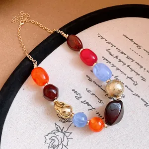 Close-up of bohemian necklace with multi-color irregular resin beads and gold accents