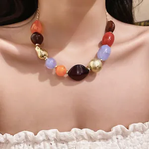 Macro detail of bohemian multi-color irregular resin bead necklace worn on neck area