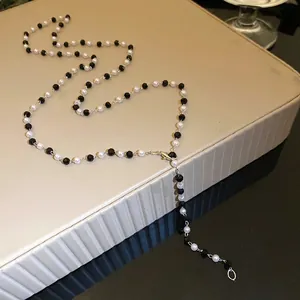Elegant black and white beaded necklace with pearls displayed on a luxury jewelry stand