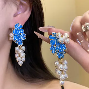Detailed macro view of vintage grape earrings with blue enamel leaves and pearls