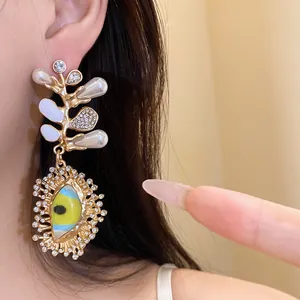 Detailed macro shot of an ornate golden earring with pearls, rhinestones and eye motif