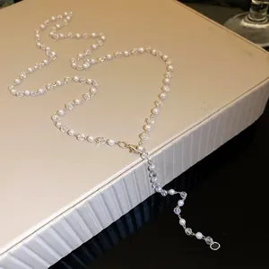 Detailed close-up of elegant pearl and crystal bead necklace on cream textured display box