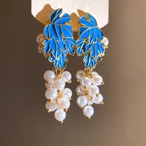 Detail showing the vibrant blue enamel leaves and pearl grape cluster design of these earrings.