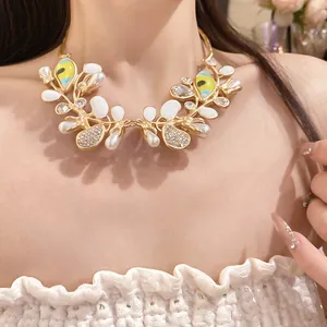 Detailed macro view of an ornate gold necklace with pearls and eye motifs on a model.