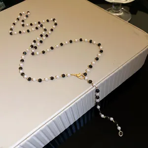 Close-up detail of black and white beaded necklace with gold finish lobster clasp
