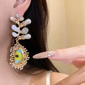 Detailed macro view of an ornate gold eye pendant earring with pearls and crystals