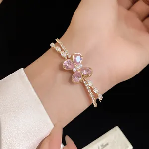 Detail shot of a double-layered gold bangle featuring a pink zircon butterfly