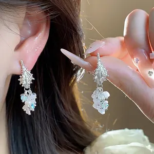Elegant conch shell tassel drop earrings with pearls and beads for a beach vacation look.