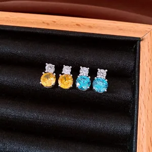 Close-up of yellow and blue round cubic zirconia stud earrings in a wooden display box