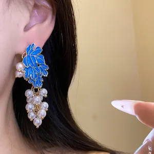 Detailed view of grape-shaped earrings with blue enamel leaves and white pearls.