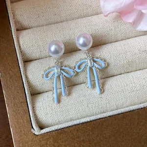 Elegant bowknot pearl earrings with blue enamel and zircon detail in a jewelry box