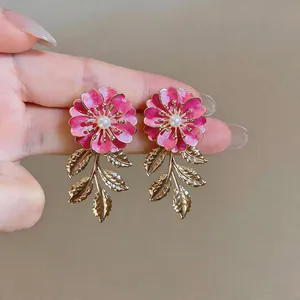 Detailansicht der rosa Emaille-Blumenohrringe mit goldenen Blattquasten und Perlen.