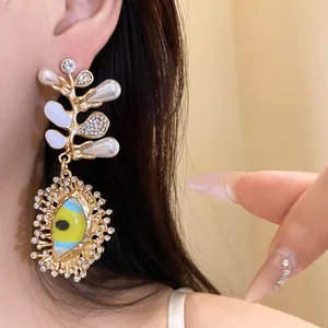 Close-up of ornate gold earring with pearls, crystals and eye motif