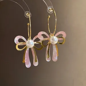 Elegant pink acetate bow earrings with gold hoops and white pearl accents for women