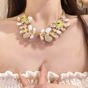Detail view of a luxury gold necklace with rhinestones and eye motifs on a model