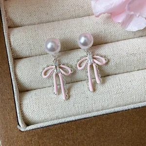 Close-up of pink enamel bow pearl stud earrings with zircon inside a jewelry box