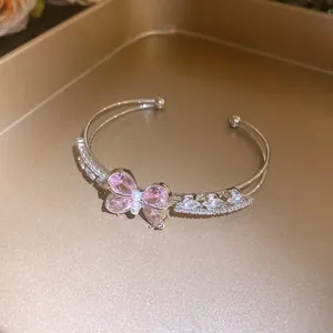 Close-up detail of an elegant pink zircon butterfly open bangle featuring delicate pearl accents