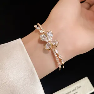 Close-up detail of a double-layered gold bracelet with a zircon butterfly motif on wrist.