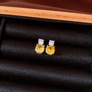 Close-up of elegant silver stud earrings with yellow and clear cubic zirconia stones