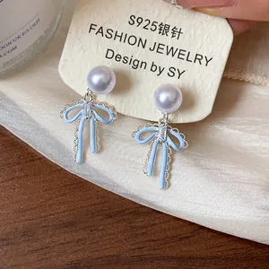 Close-up of elegant S925 silver needle pearl stud earrings with light blue bow detail