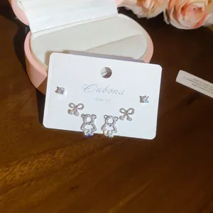 Dettaglio di orecchini a lobo a forma di orso e fiocco in argento S925 con zirconi
