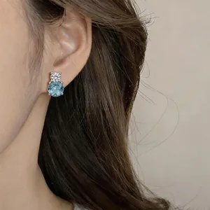 Detailed close-up showing a light blue and clear round zircon stud earring worn on ear