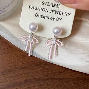 Close-up of pink bow earrings with lavender pearls and silver needle studs
