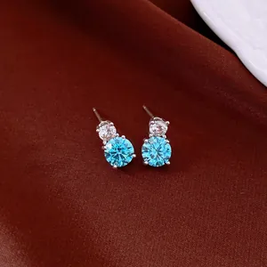 Close-up of elegant silver stud earrings with round light blue zircon stones