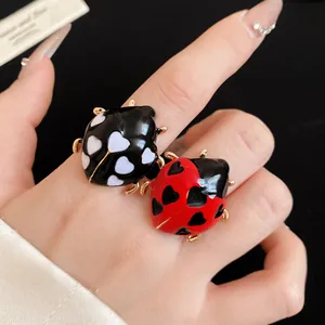 Close-up detail of stylish red and black enamel ladybug open rings with heart patterns
