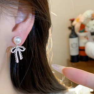 Close-up of elegant pink bow earrings featuring a white pearl and cubic zirconia accents