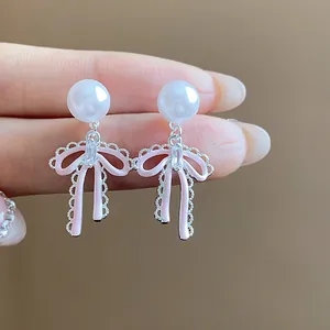 Detailed view of elegant pink bow earrings featuring white pearls and zircon stones