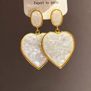 Elegant vintage gold-toned heart drop earrings with white resin mosaic pattern