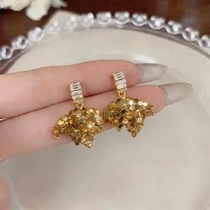 French style gold C-shaped stud earrings featuring baguette zircons and textured leaf charms