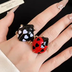 Close-up detail view of colorful drip oil ladybug rings with heart patterns worn on finger
